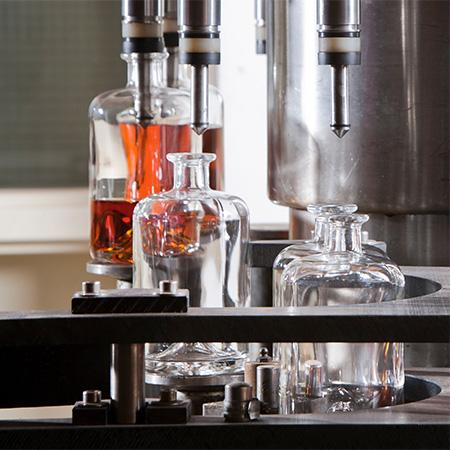 A bottle filler filling some non-alcoholic spirits bottles