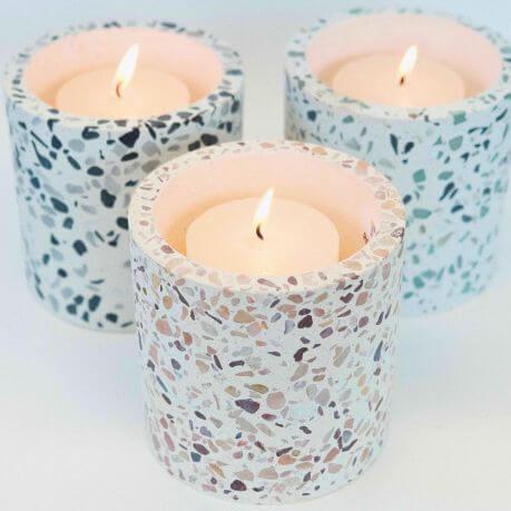 Three Terrazzo Candle Jars, with burning candles inside, on a white background.