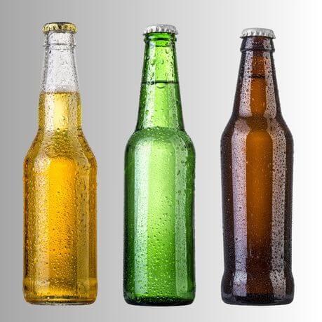 A clear, green and amber glass cider bottle, on a grey background.