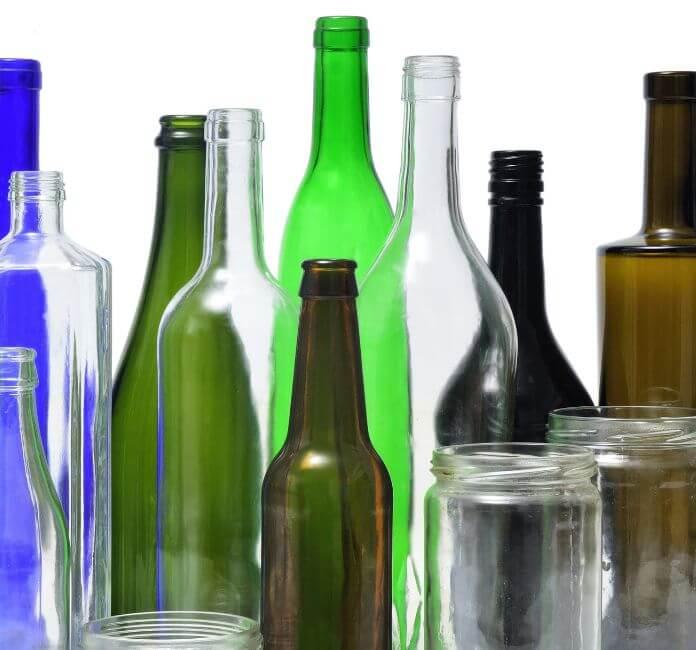 A collection of different sizes and colours of glass bottles and glass jars, on a white background.