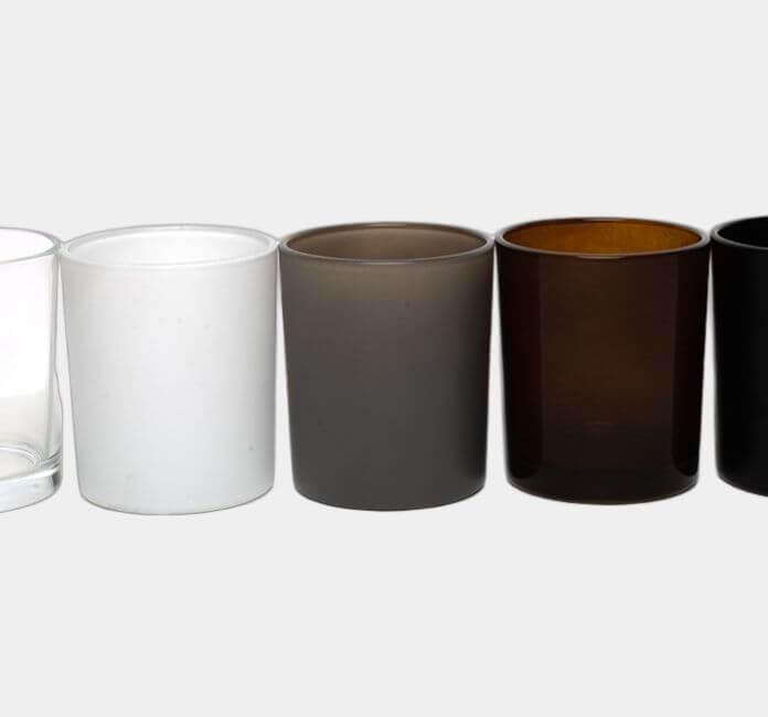 Row of glass candle jars, on a grey background.