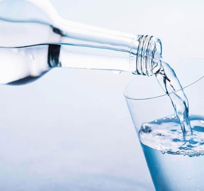 Glass bottle pouring water into a glass.