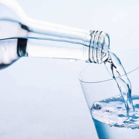 Glass bottle pouring water into a glass.