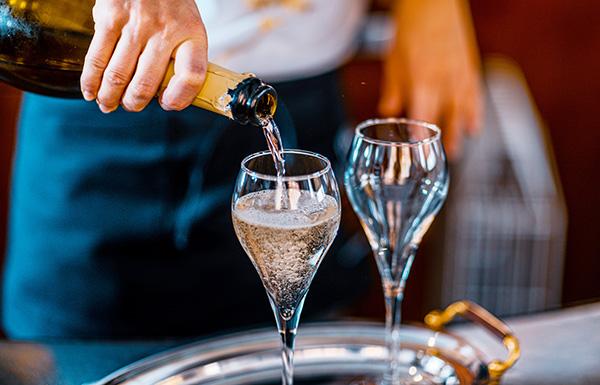A waitress pouring two glasses of sparkling wine