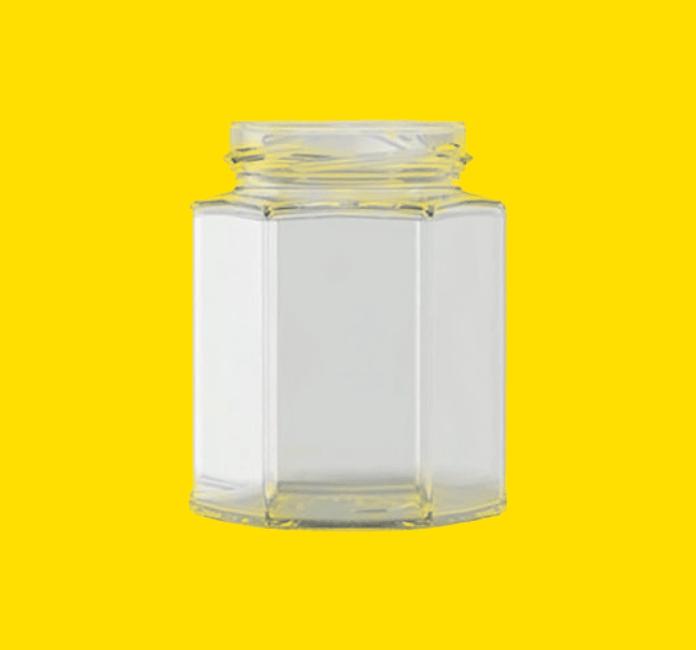Hexagonal glass honey jar on a yellow background
