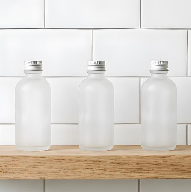 Three frosted beauty product jars on a bathroom shelf.