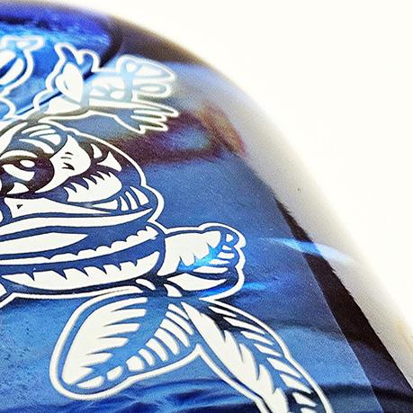 CLose up of a blue spirits bottle with screen-printed floral design